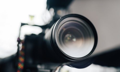 Close-up view of a professional camera lens with microphone, ideal for photography and videography enthusiasts.